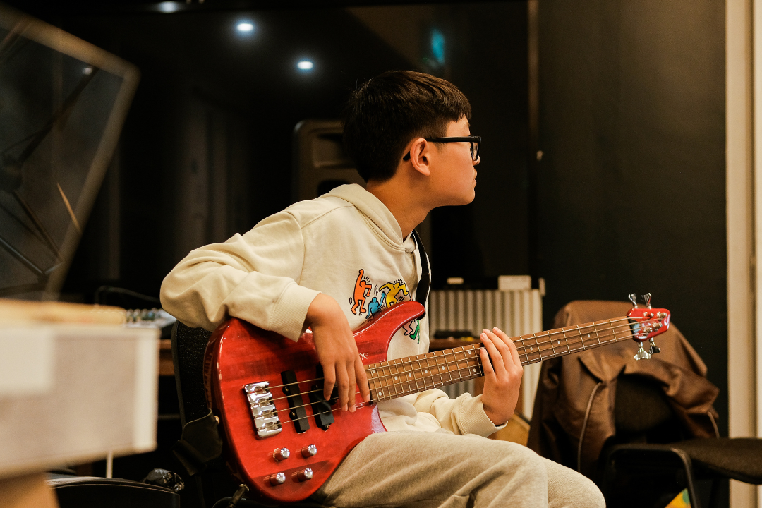 A teenager playing a red electric guitar.
