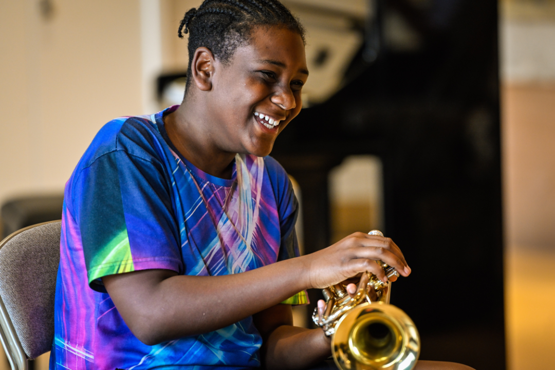 A young person laughing whilst learning the trumpet