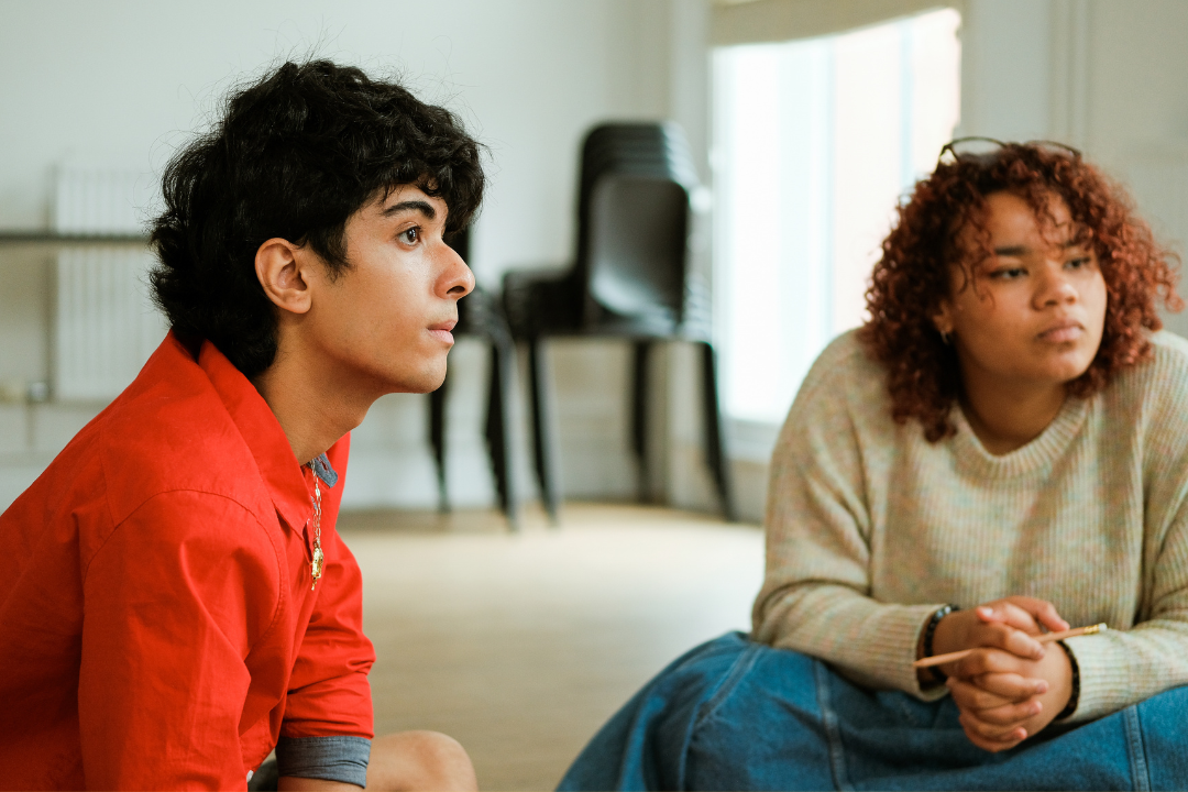 Two teenagers listening to someone off camera talking about song lyrics.