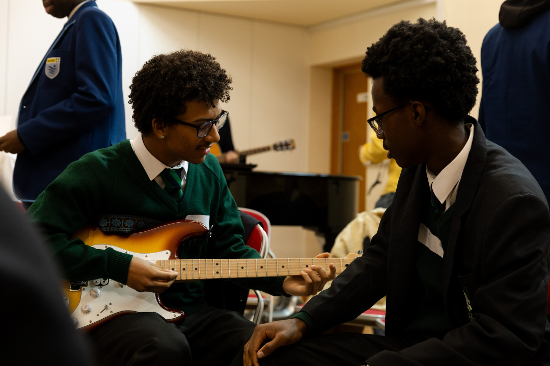 Two young people in school uniform playing the guitar.
