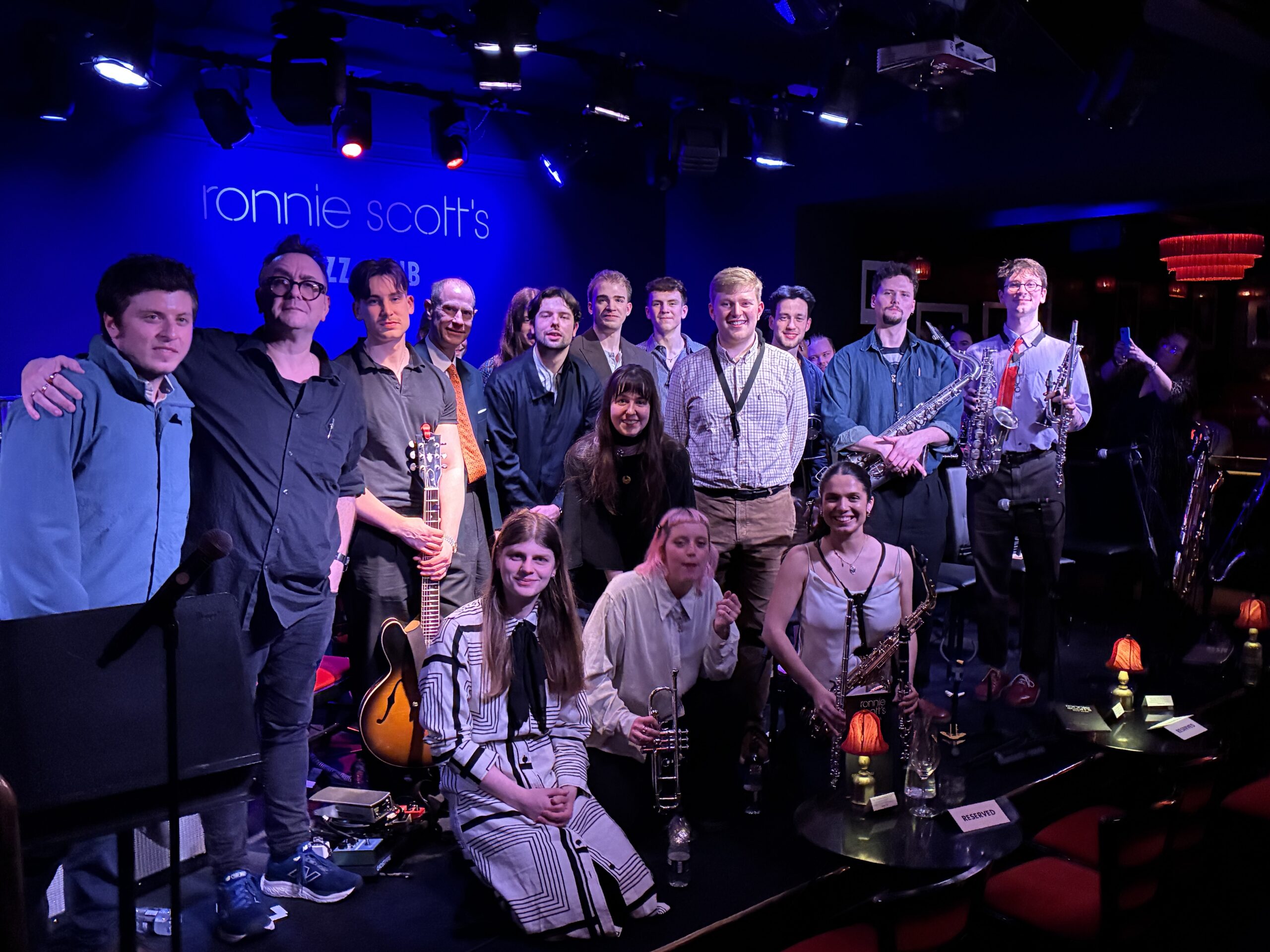 NYJO musicians in a group photo taken on the stage at Ronnie Scott's with His Royal Highness The Duke of Edinburgh
