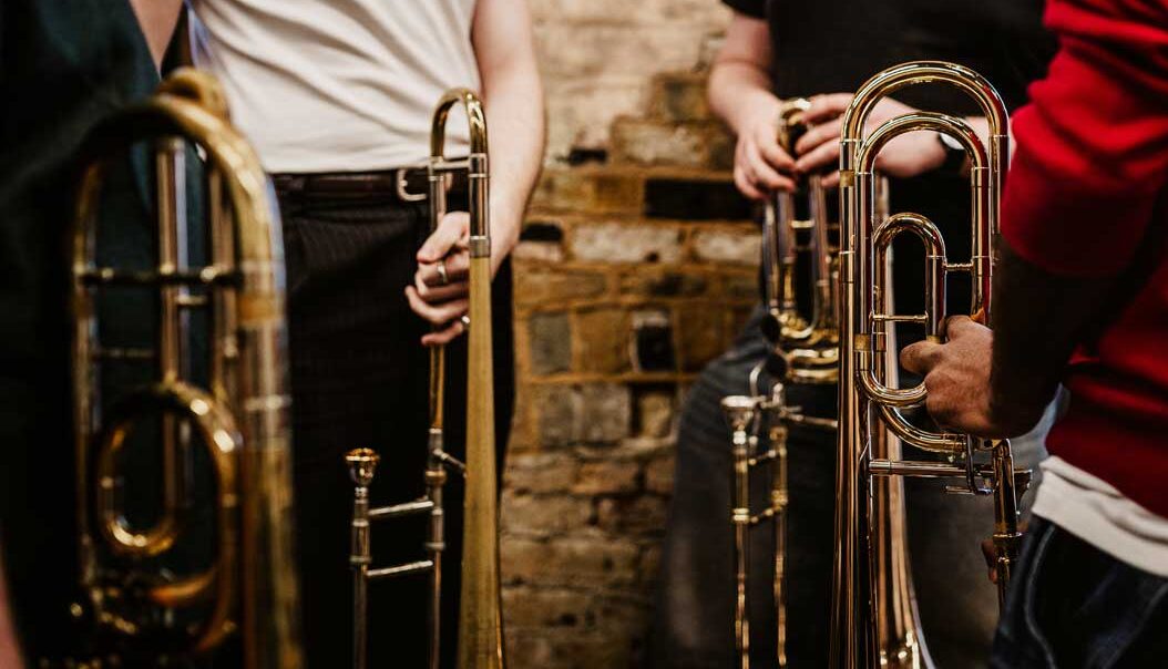 Close up of trombones being held by players who are cropped out of the shot