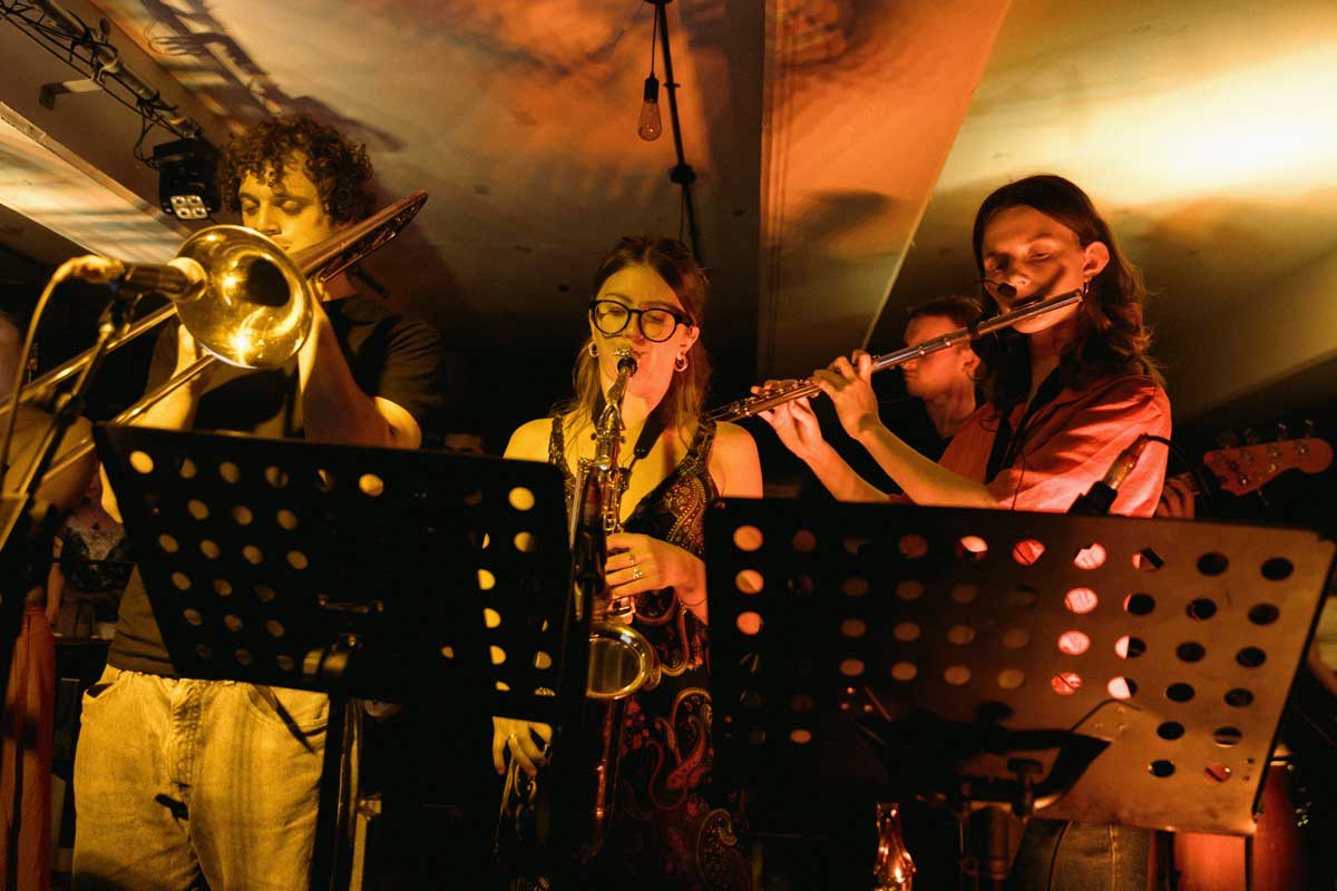 A dynamic shot with three players - a trombonist, a saxophonist and a flautist - stand performing behind music stands
